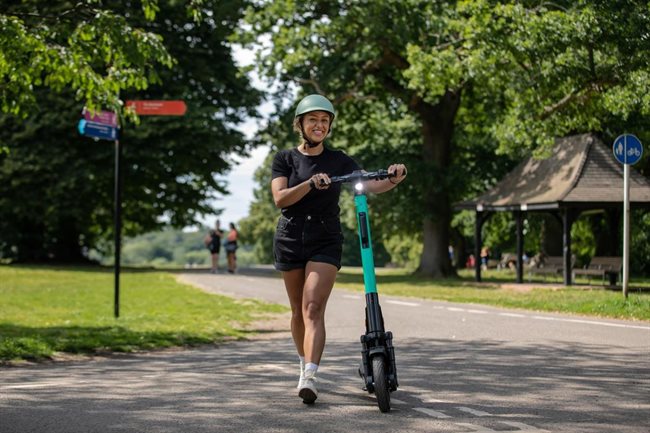 person pushing an e-scooter in a park