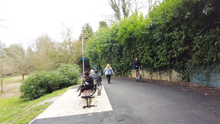 People sitting on the benches and someone walking along the new shared path in Upper Gardens