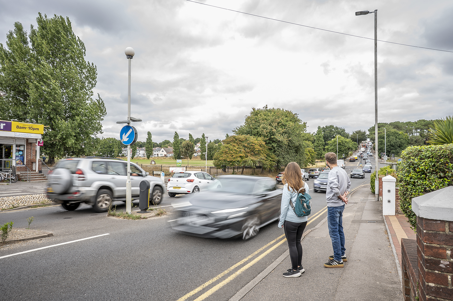 A woman and man trying to cross a busy Road on Alder Road